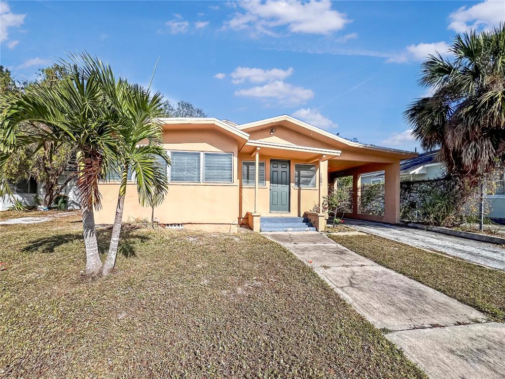 a view of a house with a yard and palm trees