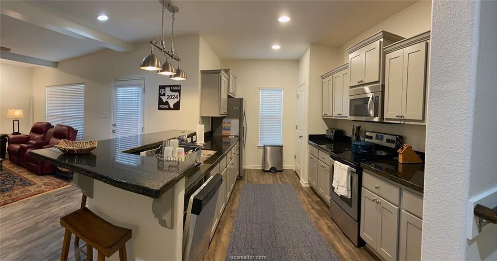 Kitchen with dark wood-type flooring, stainless st