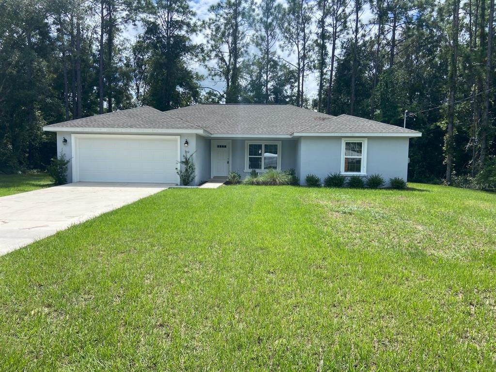 a view of a house with a yard and large trees