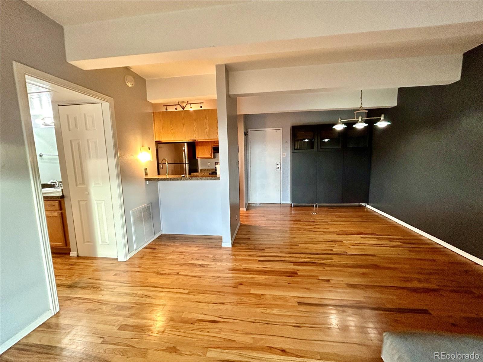 a view of a livingroom with wooden floor and a kitchen space