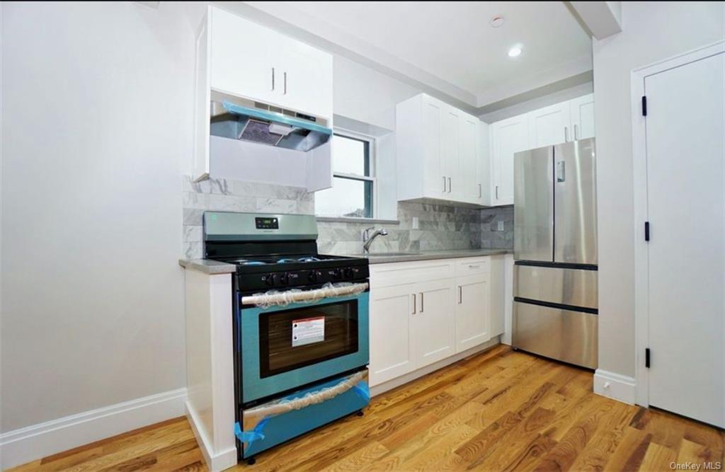 Kitchen featuring light hardwood / wood-style floors, sink, stainless steel appliances, and white cabinets