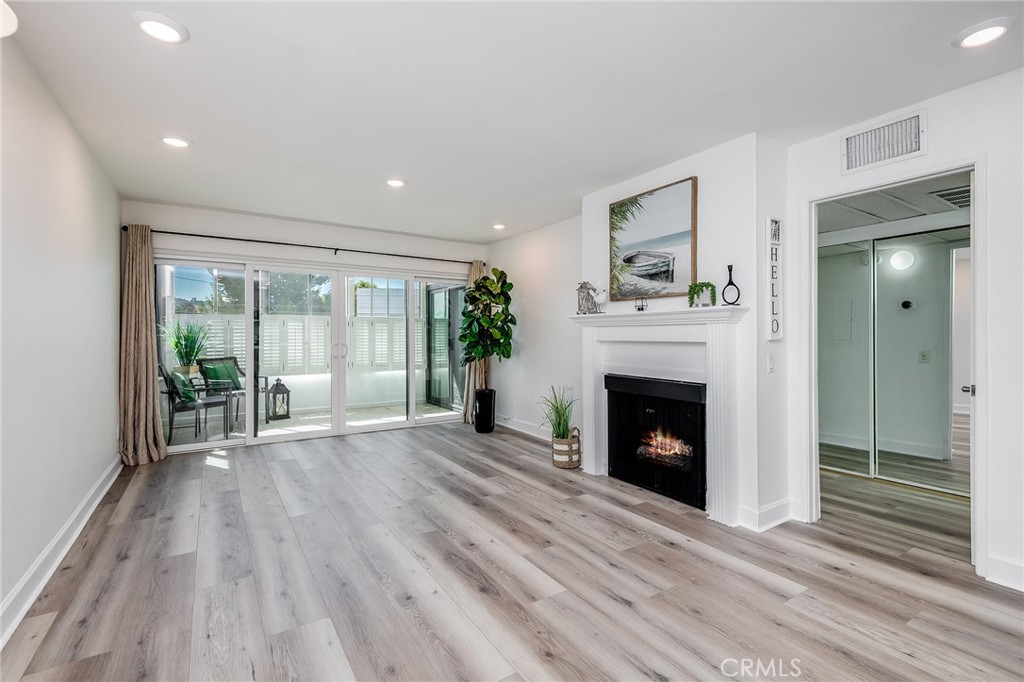 a view of an empty room with wooden floor fireplace and a window