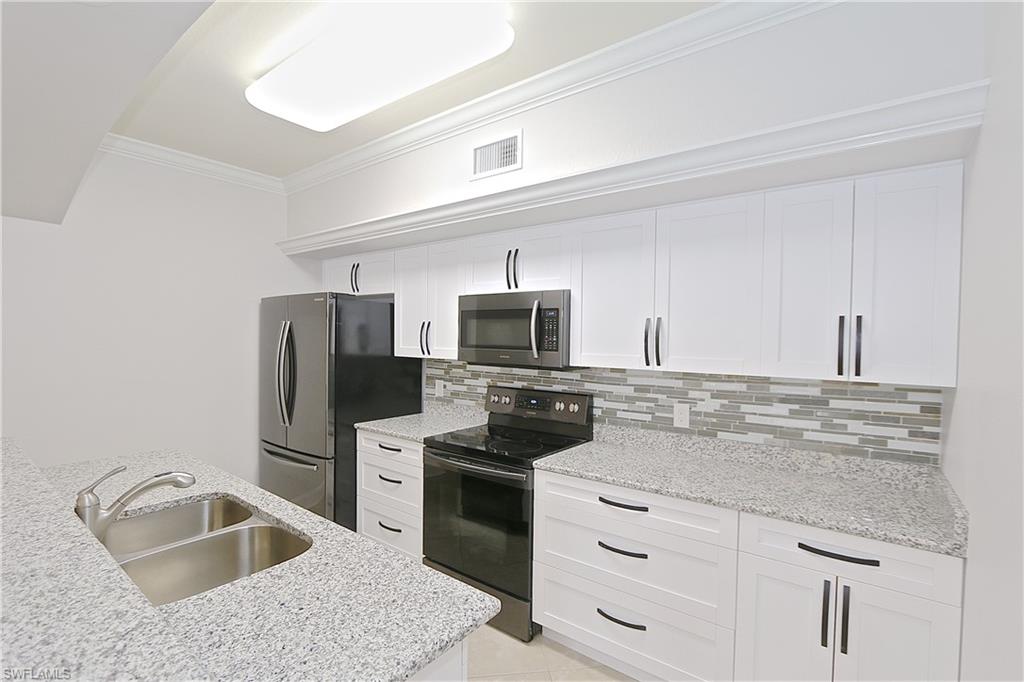 a kitchen with granite countertop a sink wooden floor and stainless steel appliances