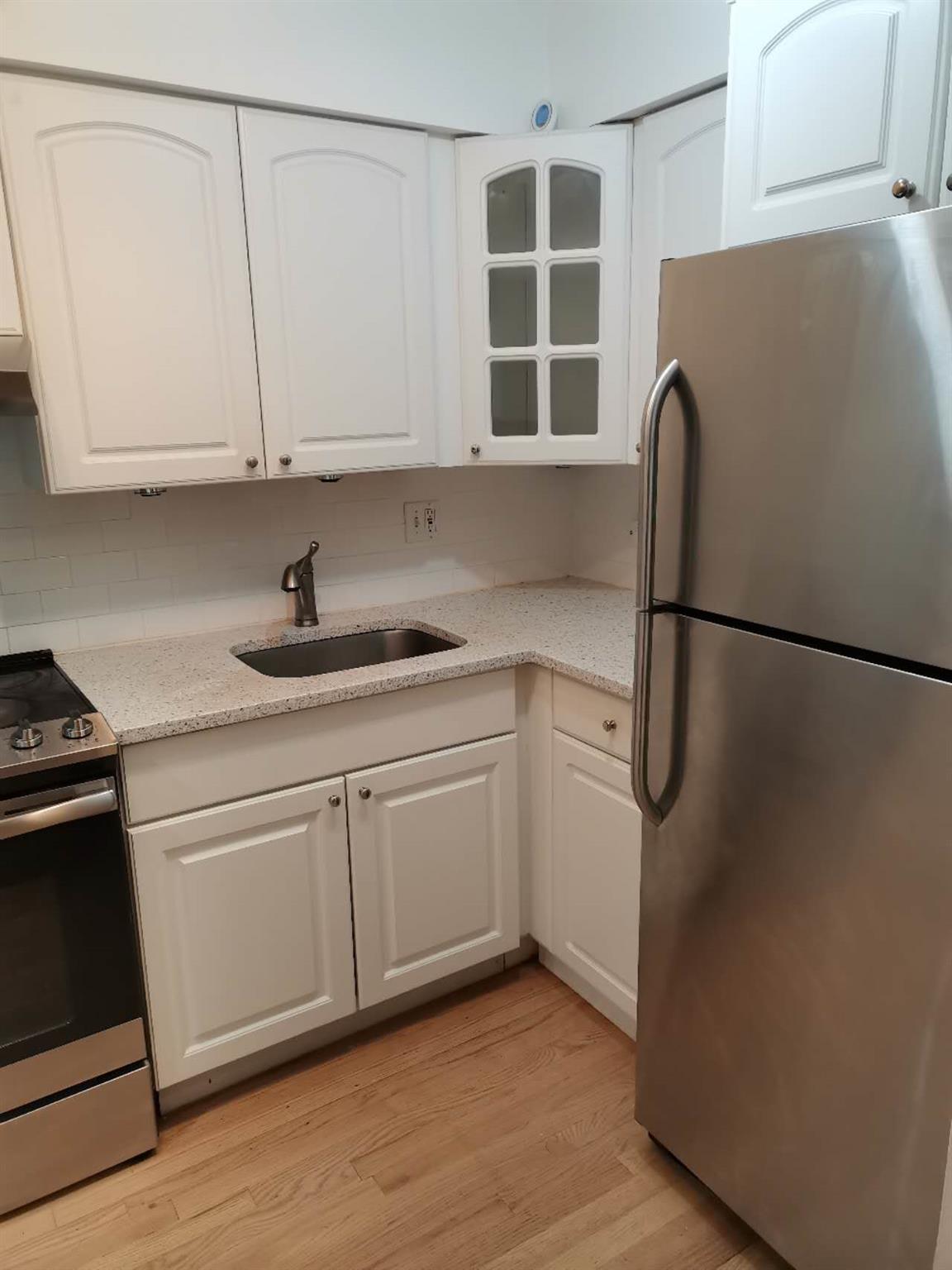 Kitchen with light hardwood / wood-style flooring, white cabinets, stainless steel appliances, and sink