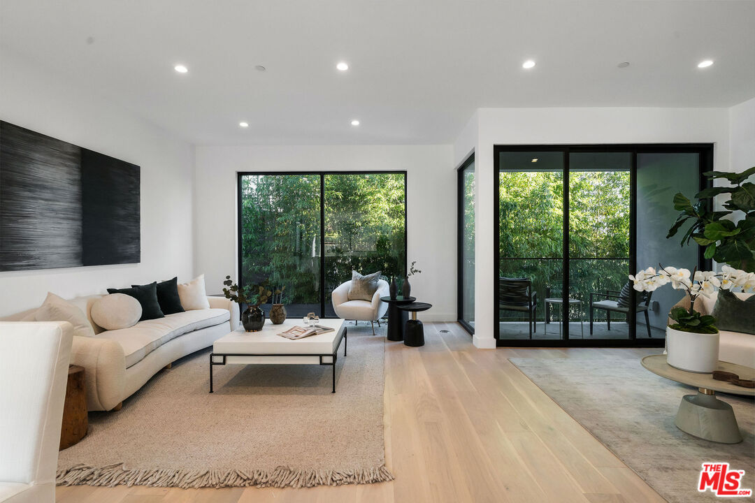 a living room with furniture floor to ceiling window and a flat screen tv