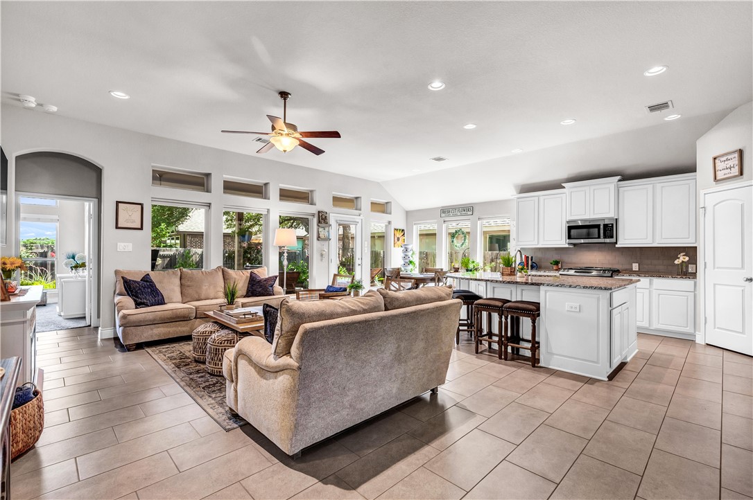 a living room with furniture kitchen view and a large window