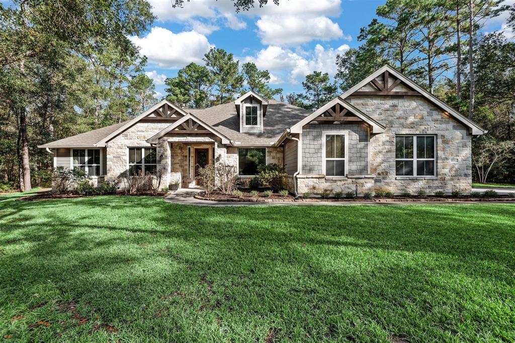 Charming single-story home with a stone facade, situated on a spacious, well-manicured lawn surrounded by mature trees. The property features large windows for ample natural light and a welcoming front porch. Ideal for those seeking a serene, picturesque setting.