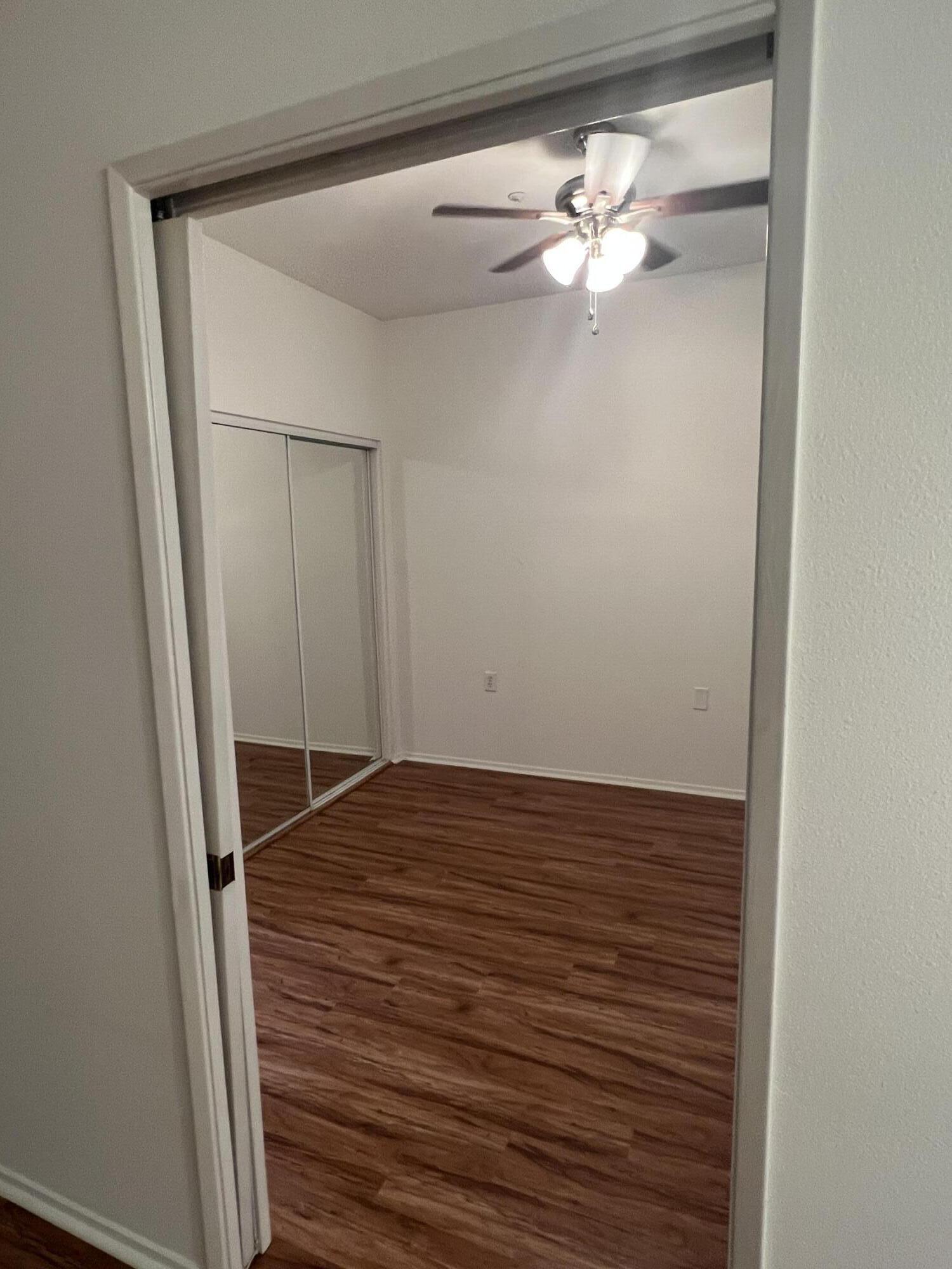 a view of a small space with wooden floor and a chandelier fan