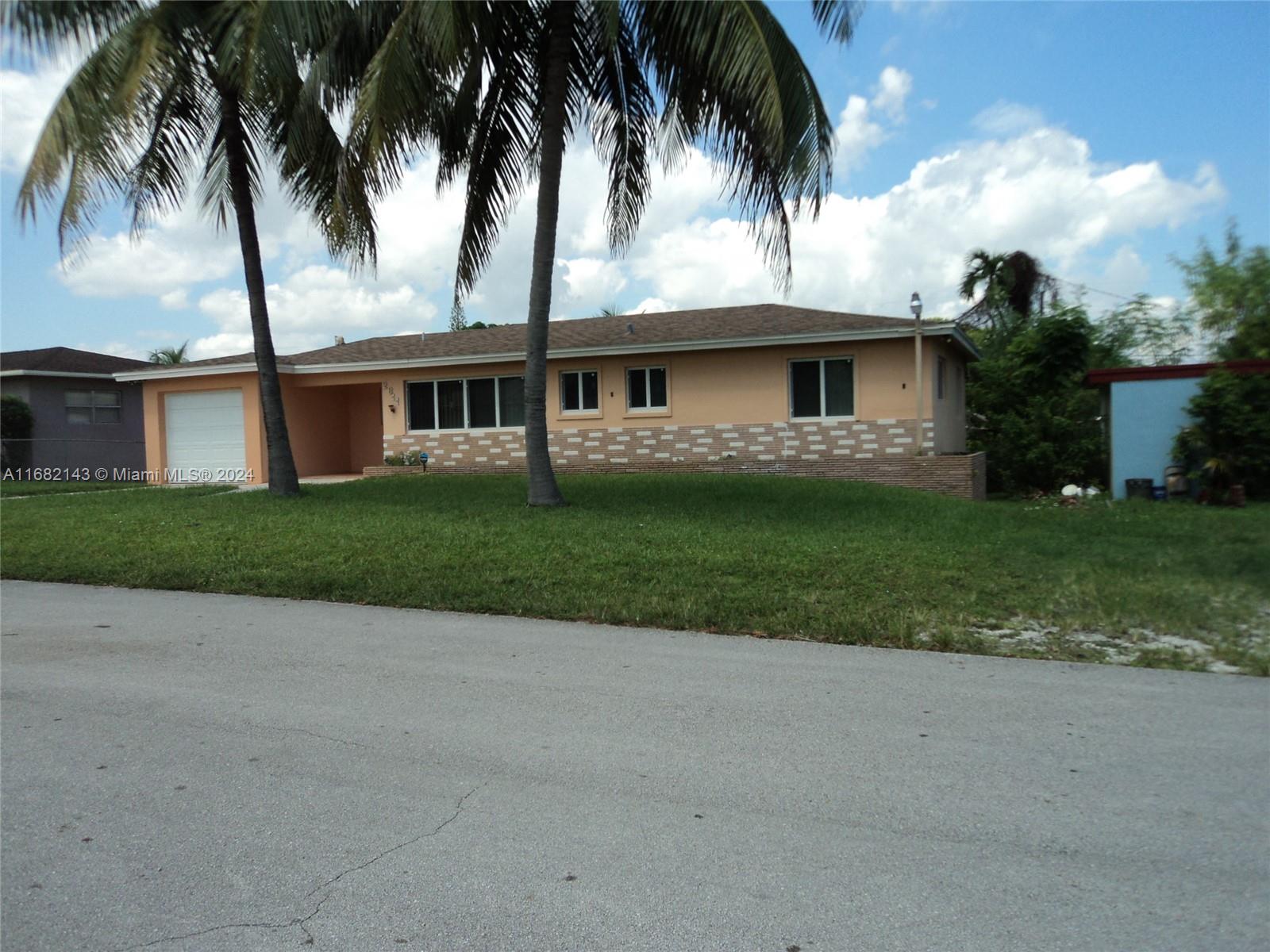 a front view of a house with a garden and palm trees