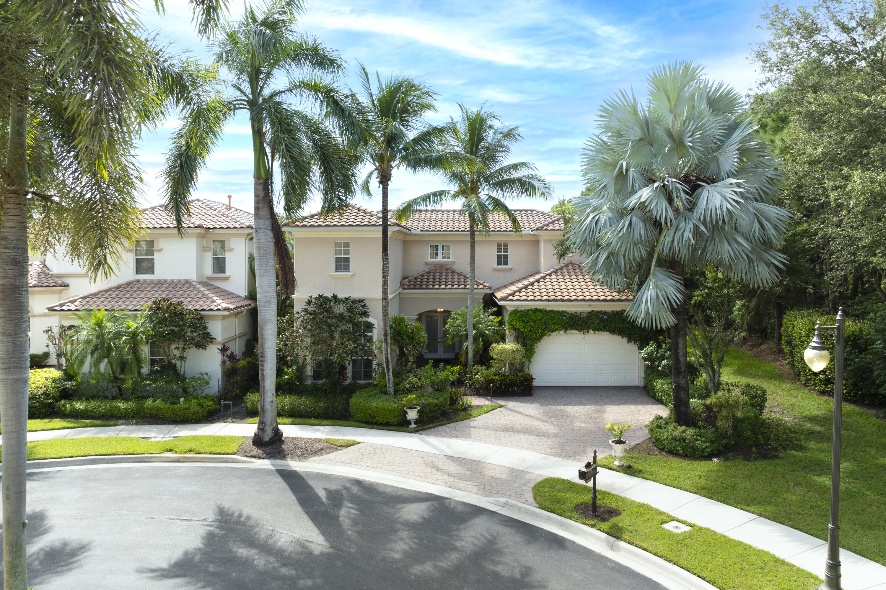 a view of yellow house with swimming pool lawn chairs and palm trees