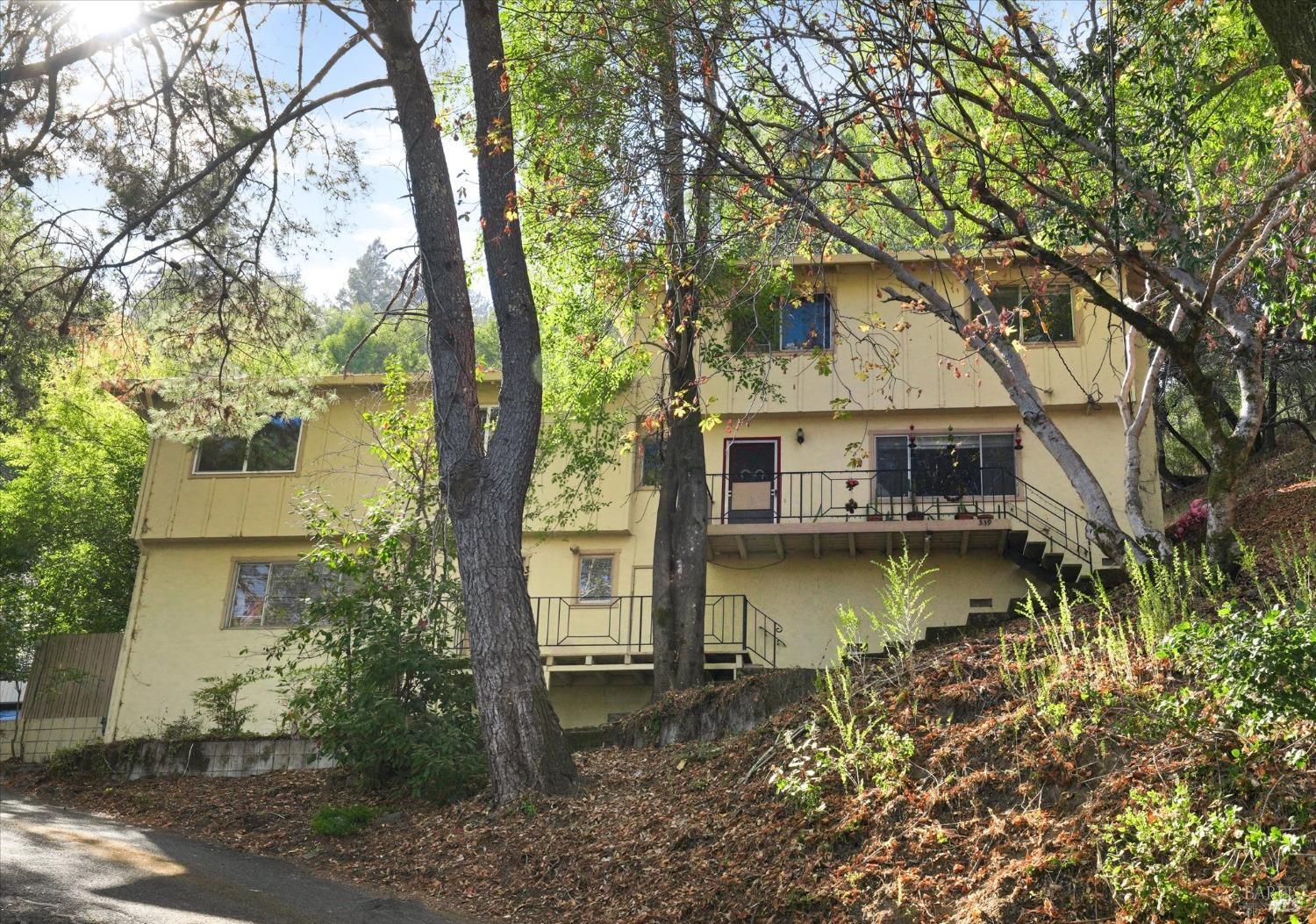 a view of a house with large trees next to a yard