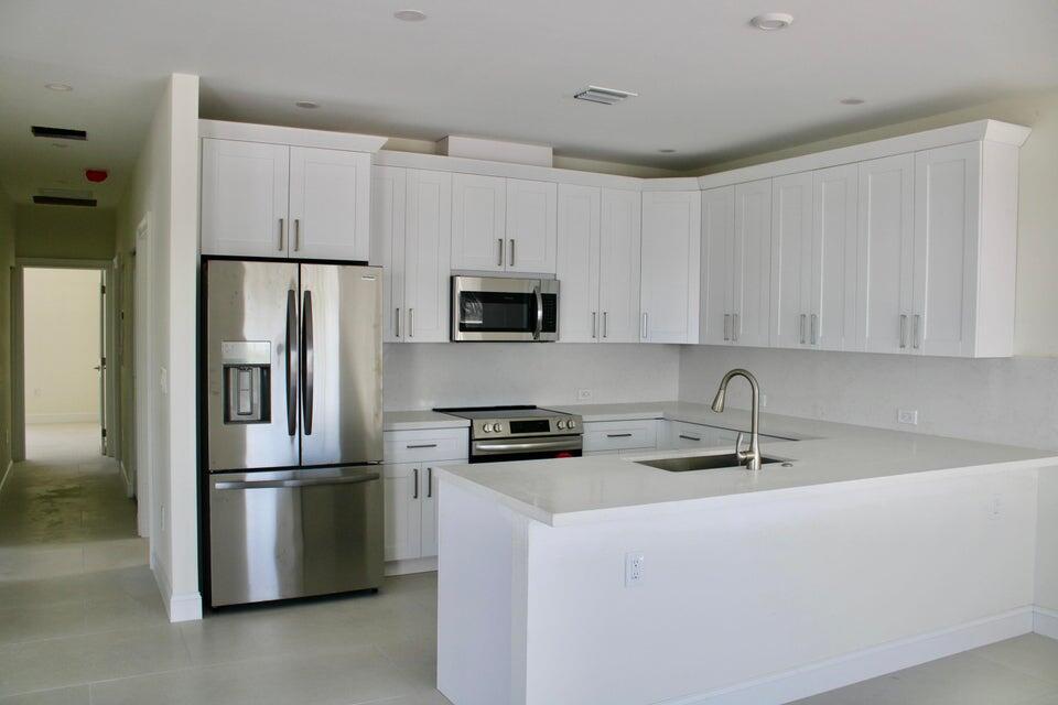 a kitchen with stainless steel appliances granite countertop a refrigerator sink and white cabinets