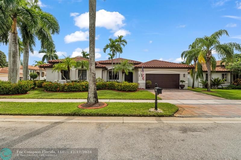 a front view of a house with a garden and palm tree