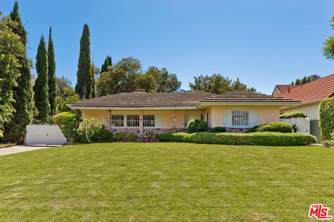 a front view of a house with a yard and potted plants