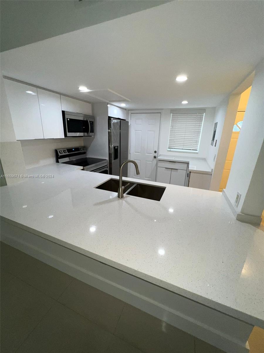 a kitchen with a sink a counter top space cabinets and appliances