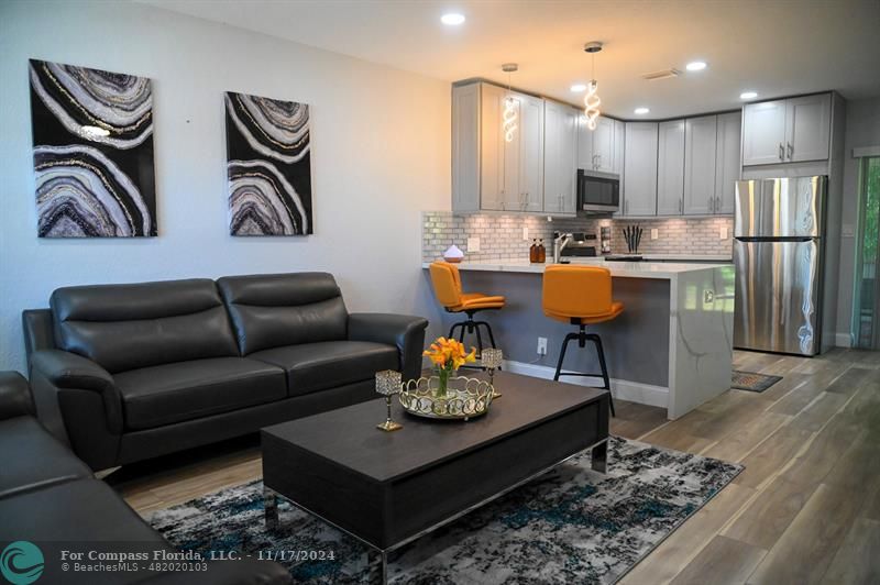 a living room with kitchen couches kitchen view and a wooden floor