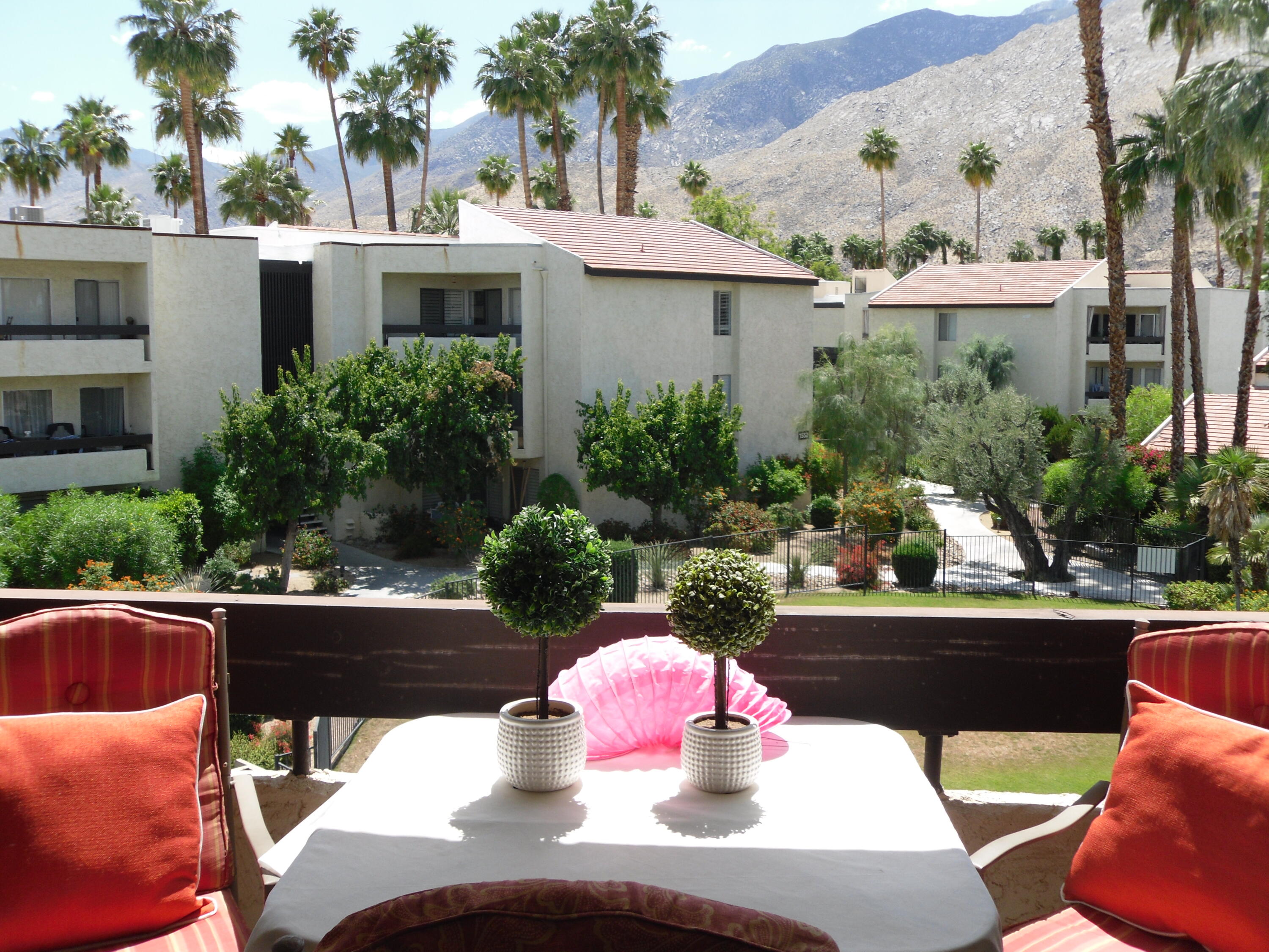 a view of a patio with couches table and chairs potted plants and palm tree