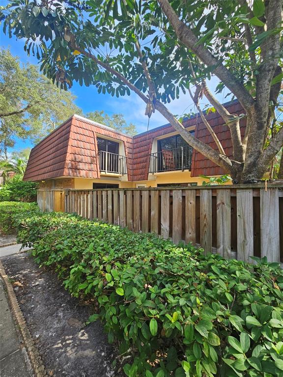 a view of a house with brick walls plants and large tree