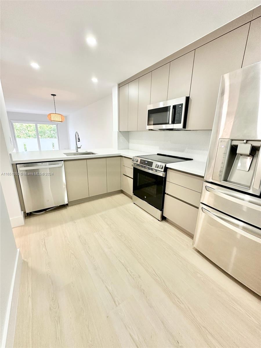 a kitchen with stainless steel appliances a refrigerator sink and microwave