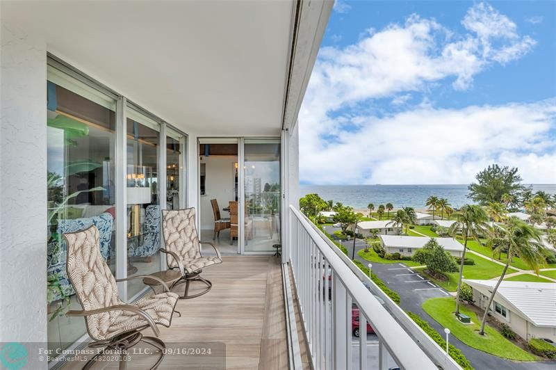 a balcony with wooden floor and outdoor seating