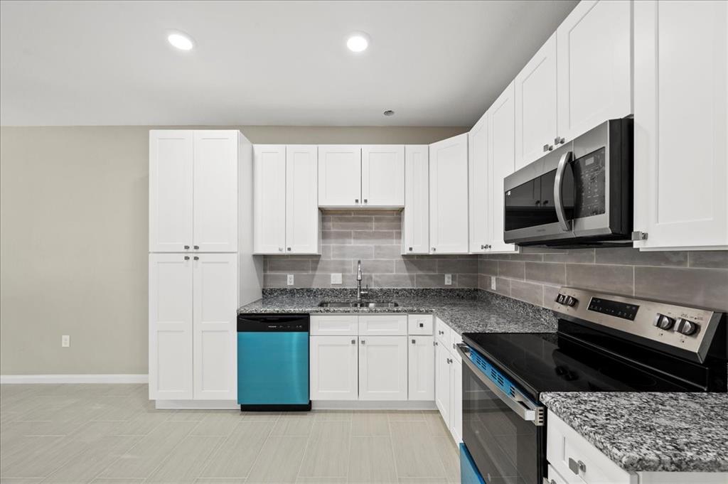 a kitchen with stainless steel appliances granite countertop a stove a sink and a microwave