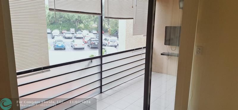 a view of a balcony with wooden floor and a potted plant next to a window