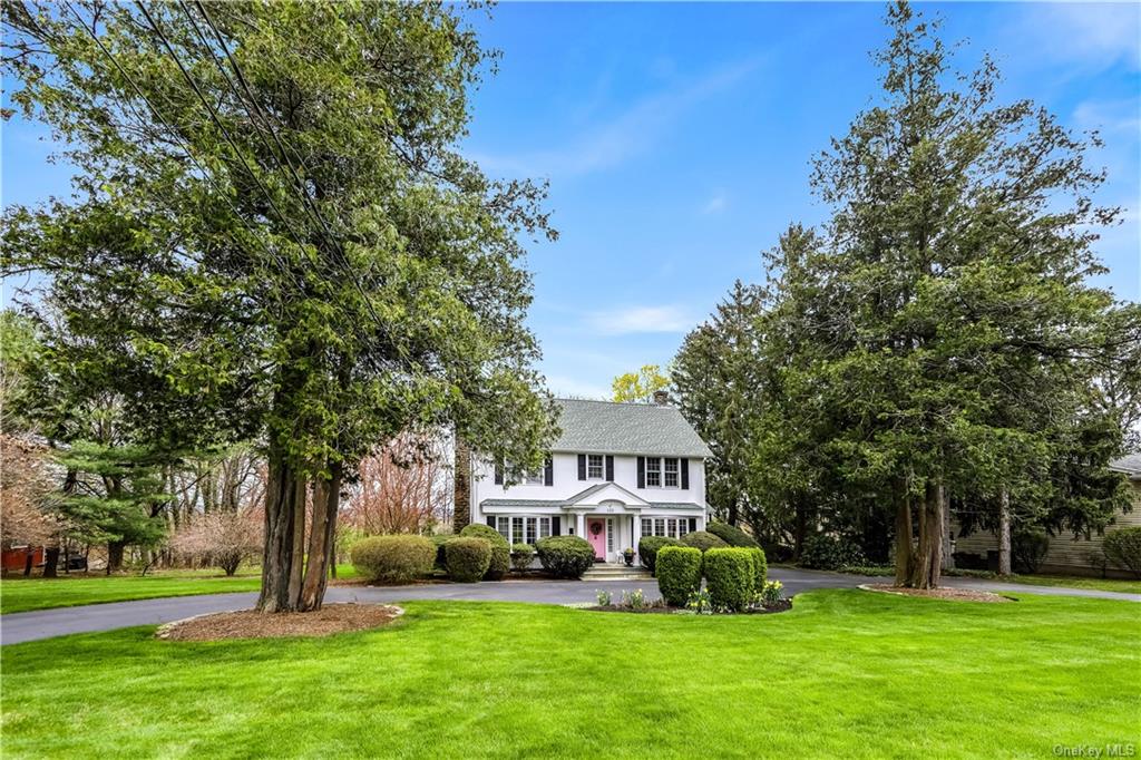 a front view of a house with garden and trees