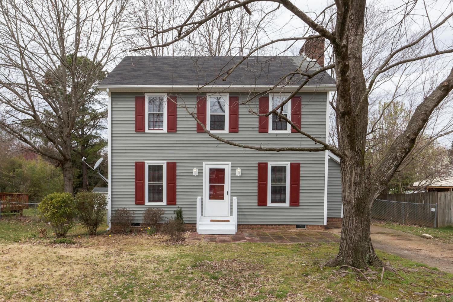 a brick house that has a large tree in front of it