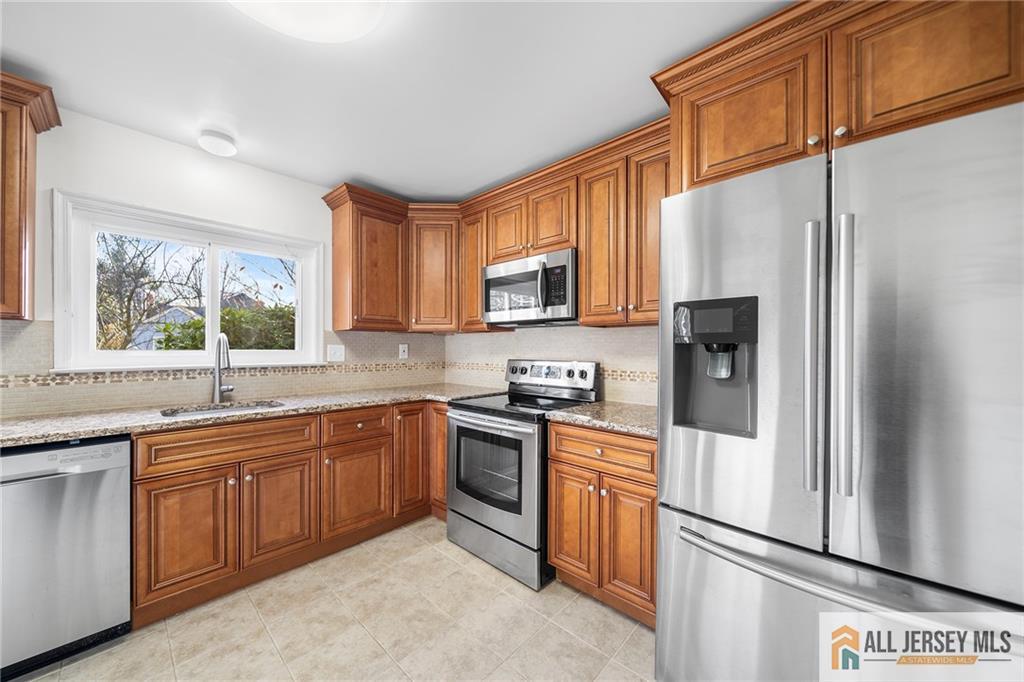 a kitchen with stainless steel appliances granite countertop a refrigerator sink and stove