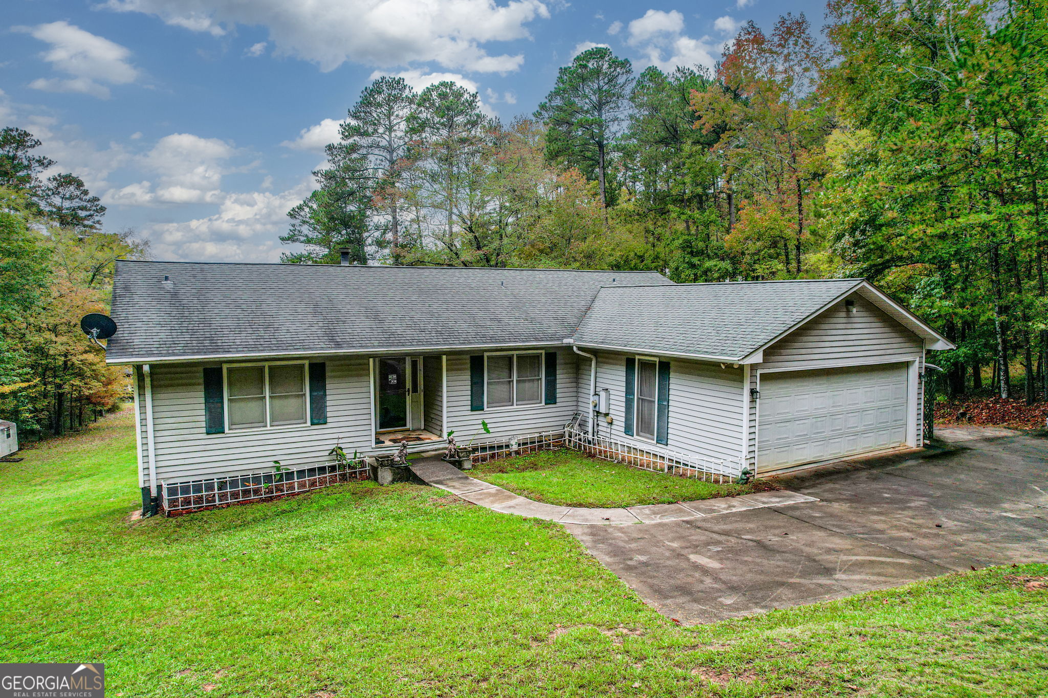 a view of a house with a yard plants and large tree