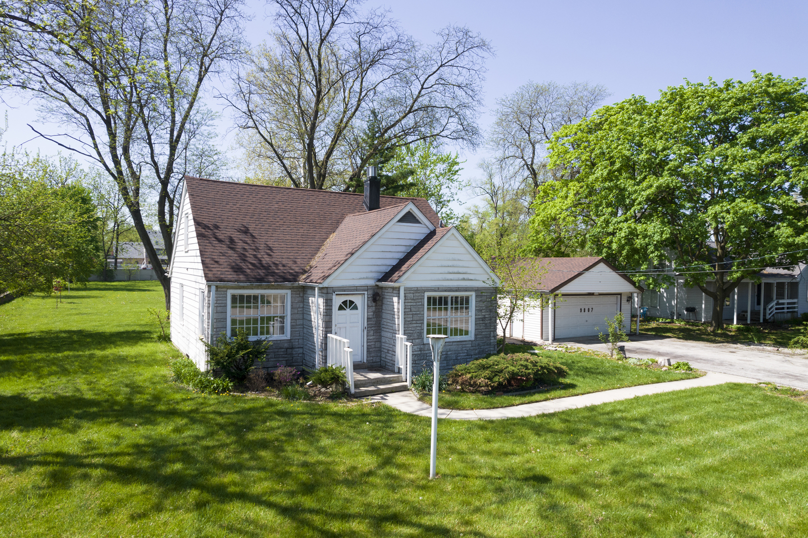 a view of a house with a big yard plants and large trees