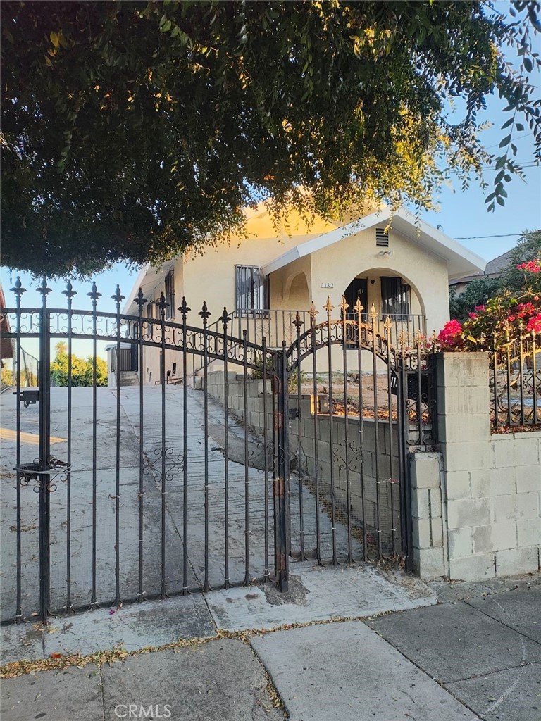 a view of a brick house with a large tree and wooden fence