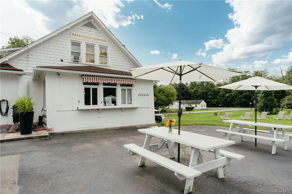 a view of a white house with a yard table and chairs