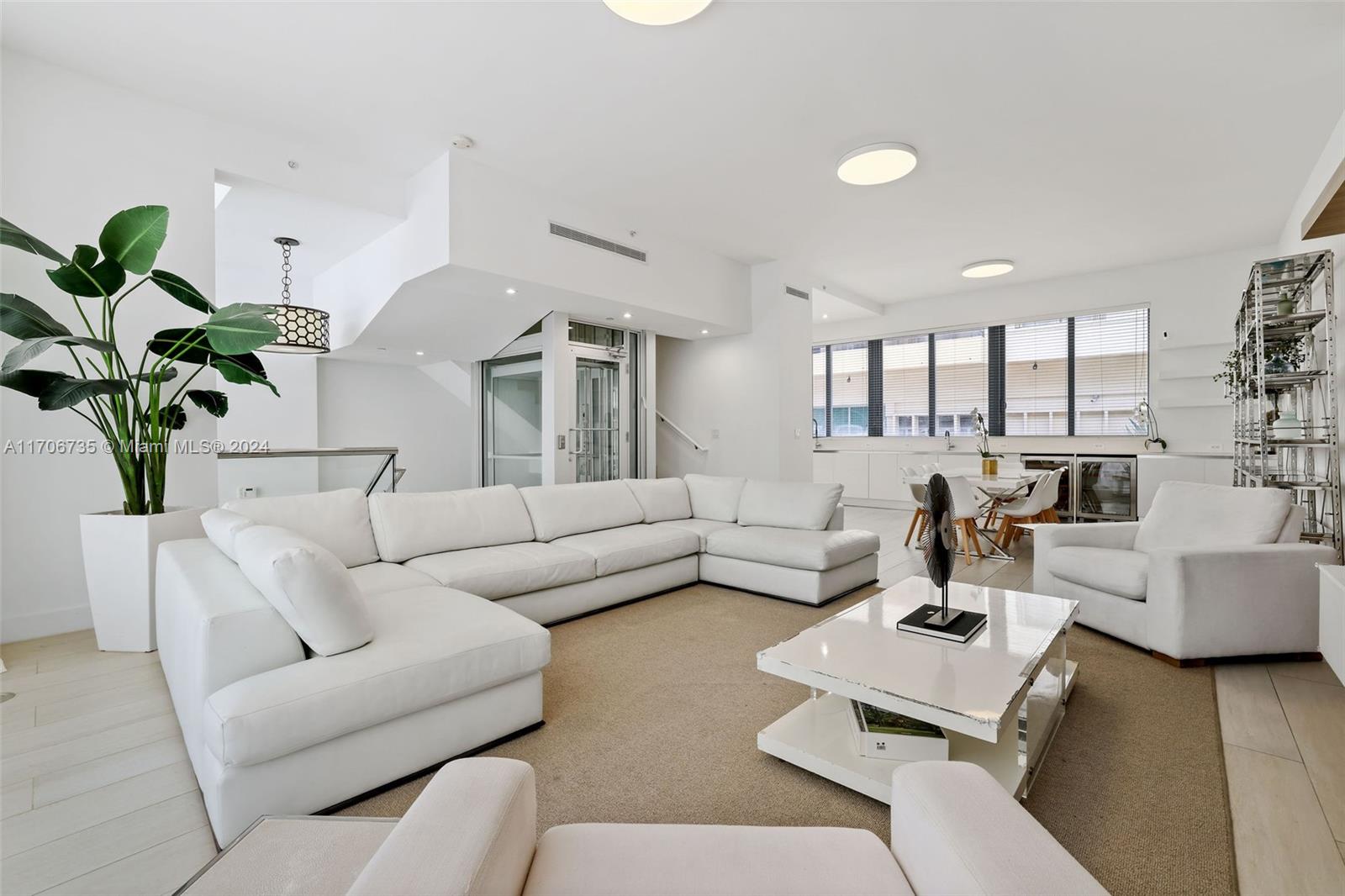 a living room with furniture kitchen view and a potted plant