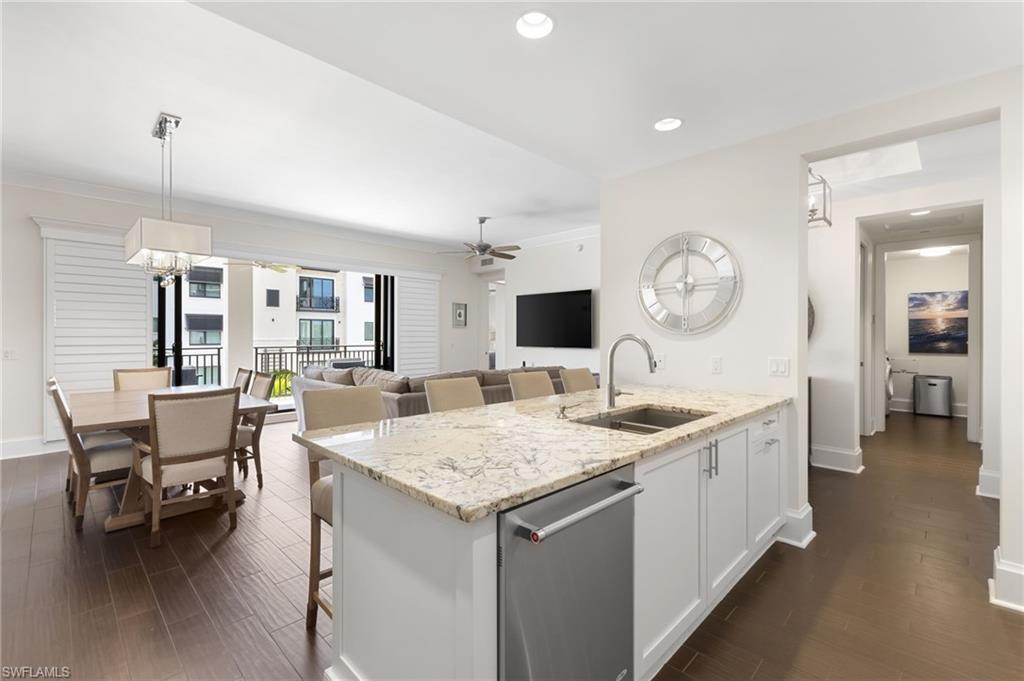 Kitchen featuring white cabinetry, dishwasher, ceiling fan with notable chandelier, dark wood-type flooring, and sink