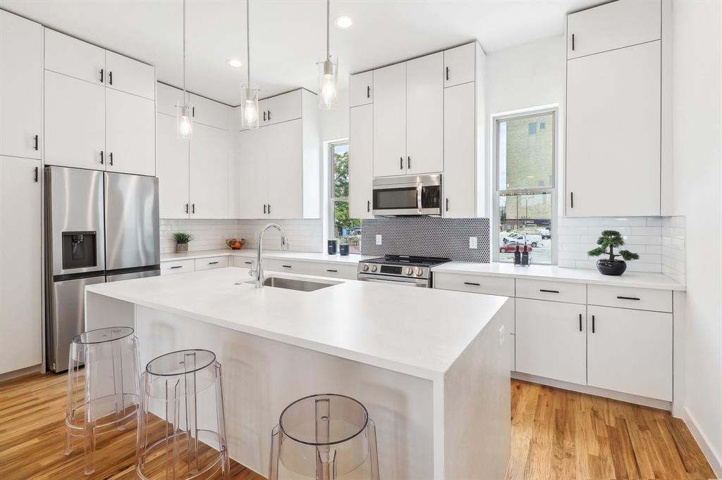 a kitchen with a sink a stove a refrigerator and white cabinets