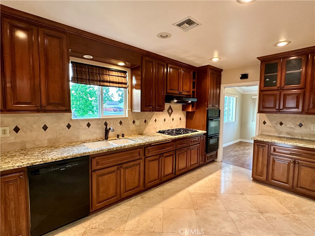 a large kitchen with stainless steel appliances granite countertop a sink counter space cabinets and a large window