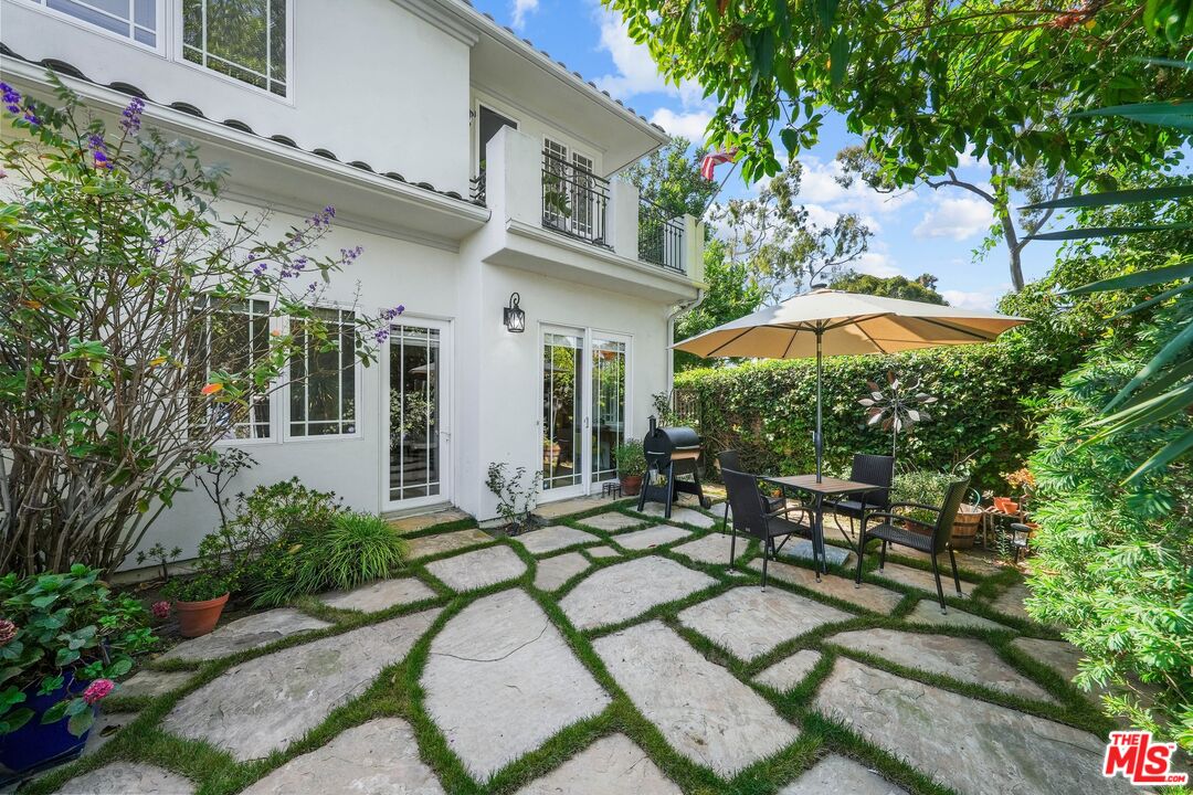 a backyard of a house with table and chairs under an umbrella