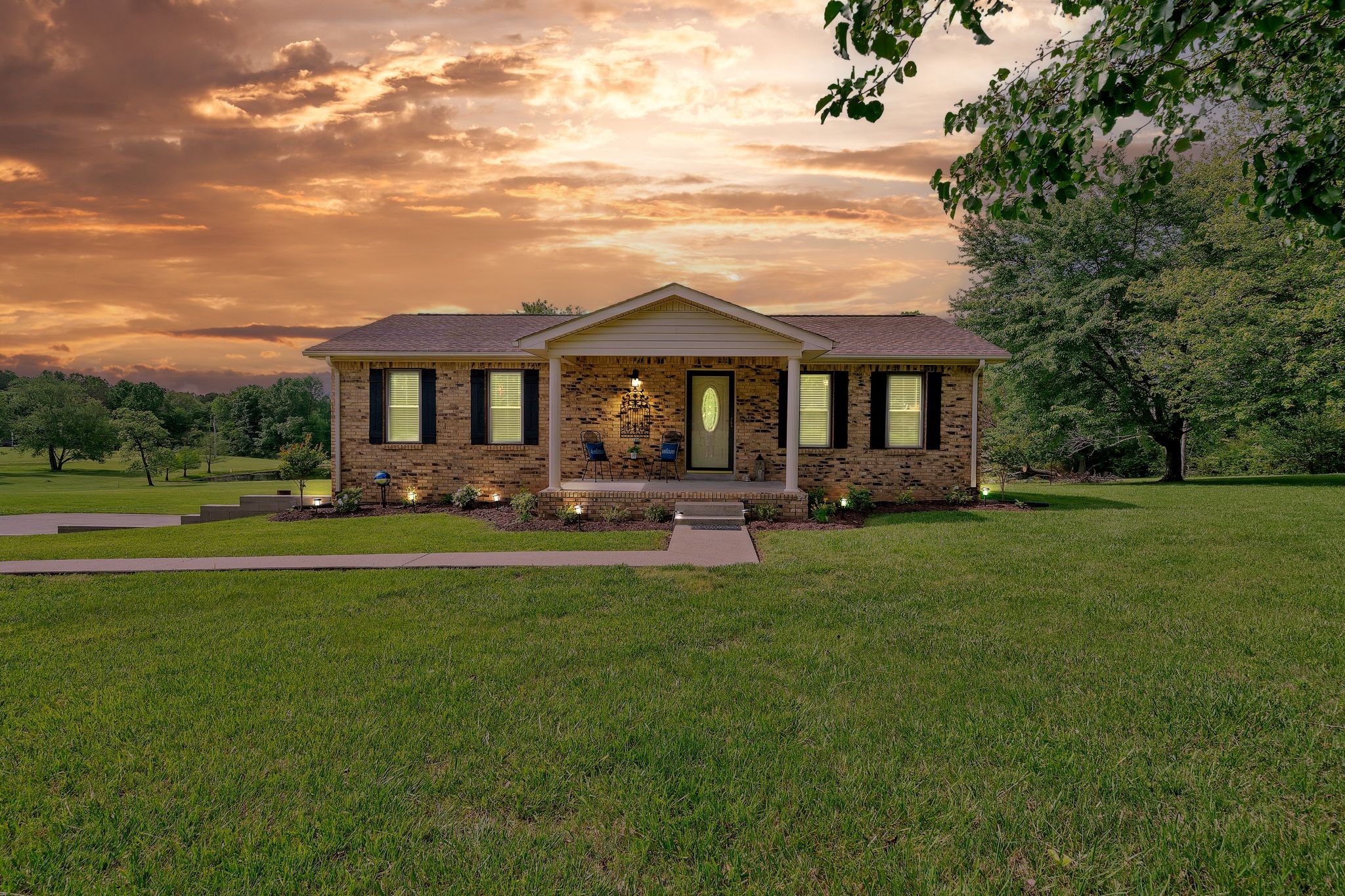 a front view of a house with a garden and trees