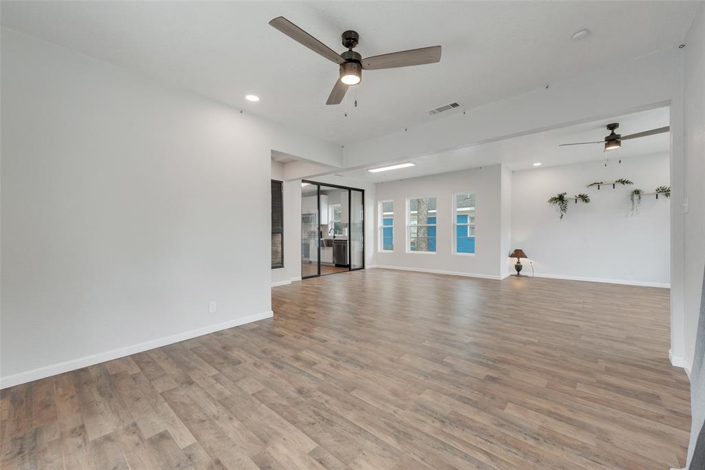 a view of an empty room with window and wooden floor