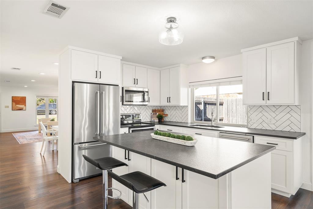 a kitchen with stainless steel appliances a table and chairs in it