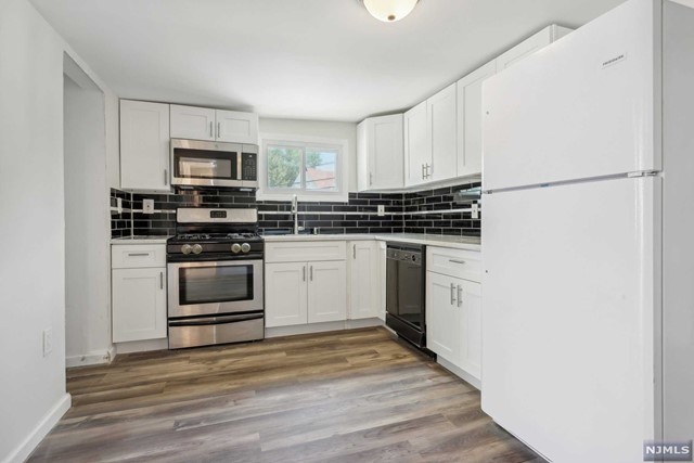 a kitchen with stainless steel appliances a stove a microwave and white cabinets