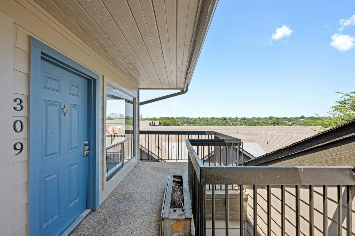 a view of a balcony with wooden floor & fence