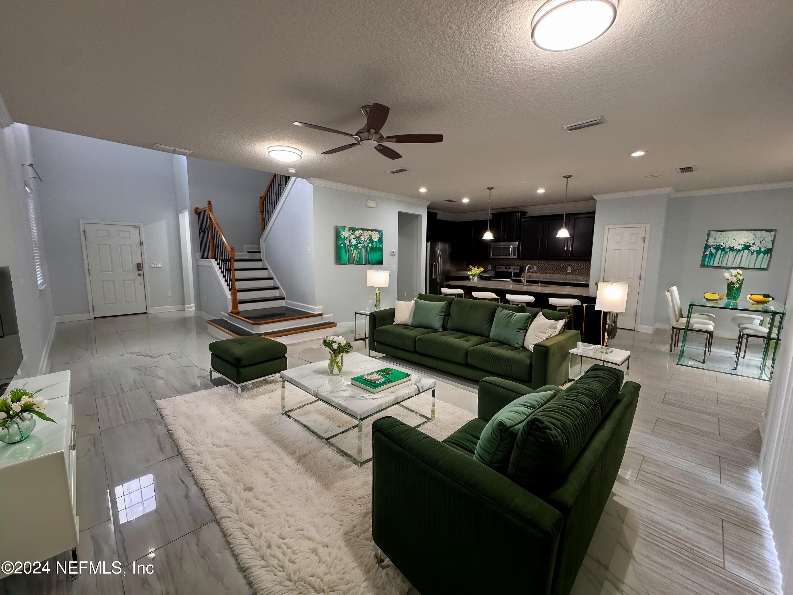 a living room with furniture kitchen view and a wooden floor