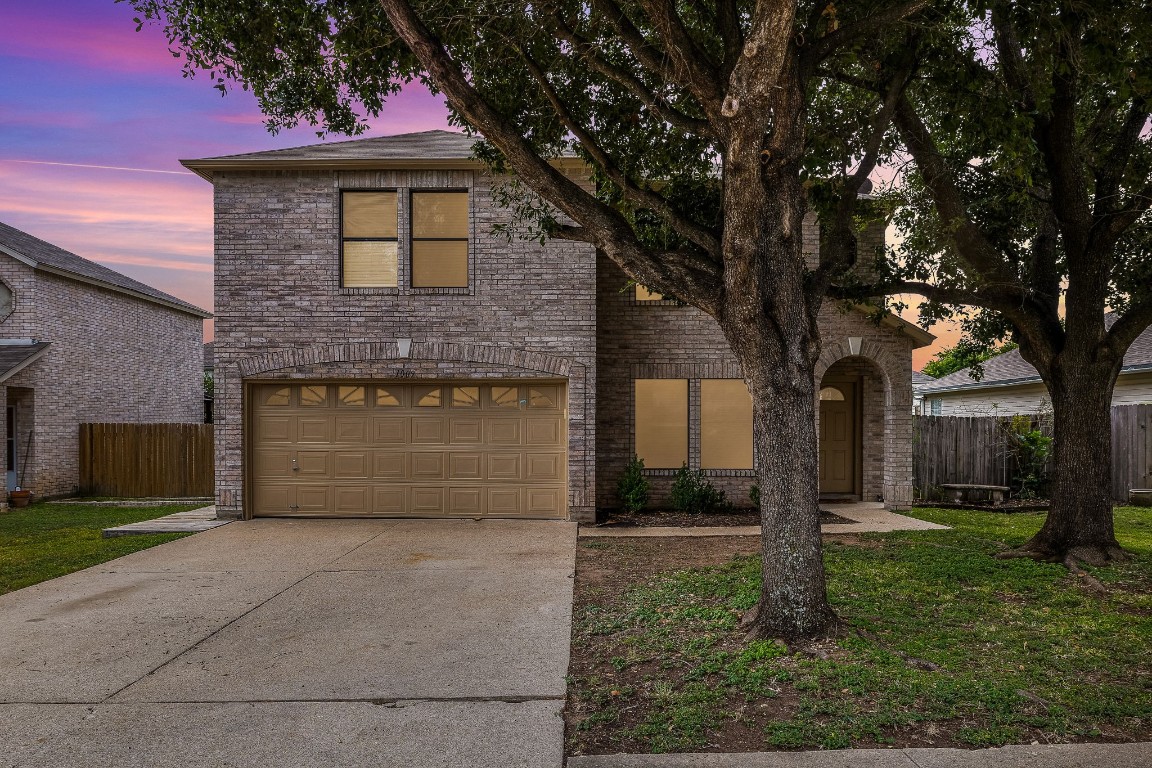 a front view of a house with a yard and tree