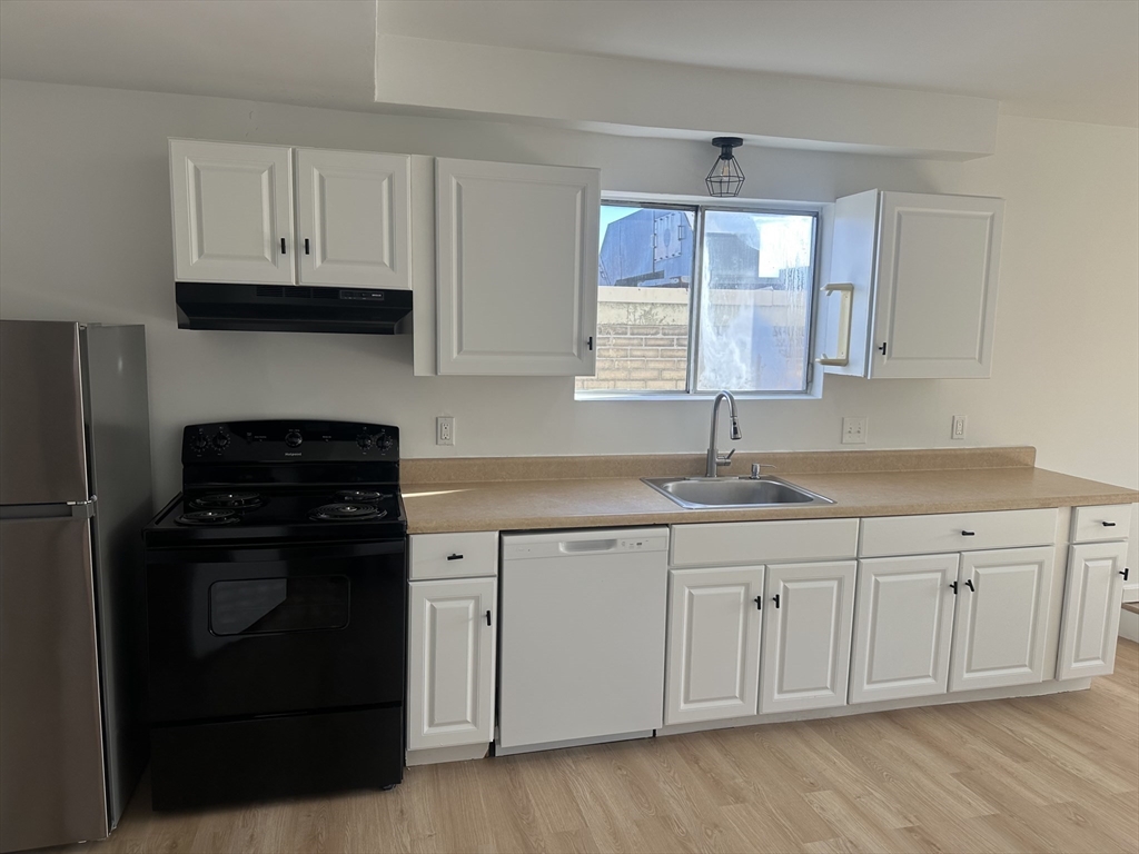 a kitchen with granite countertop white cabinets and black appliances