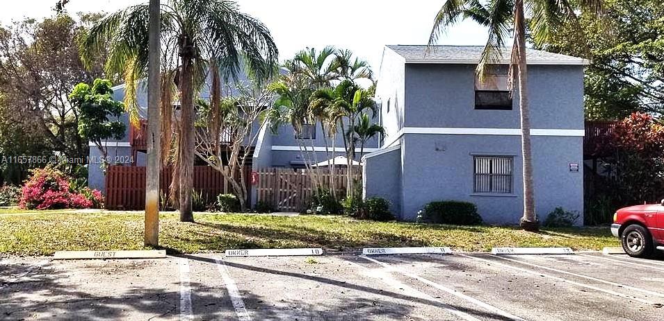 a front view of a house with a yard and palm trees