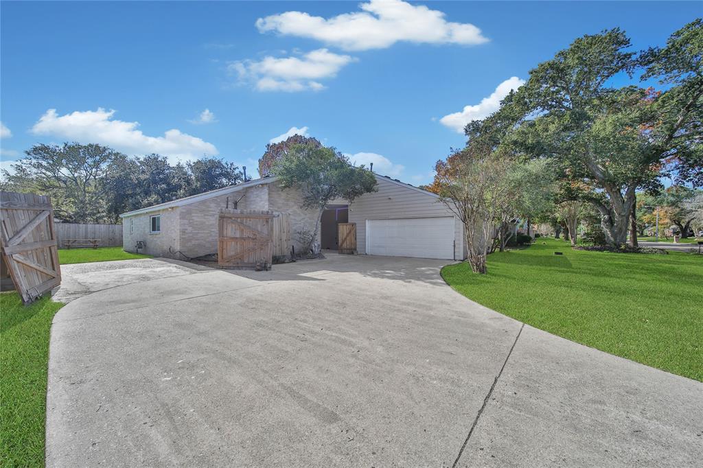 a view of a house with a yard and large trees