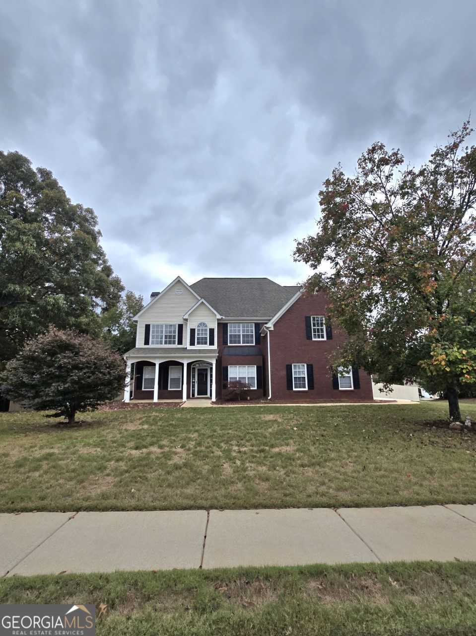 a view of a big house with a big yard and large trees