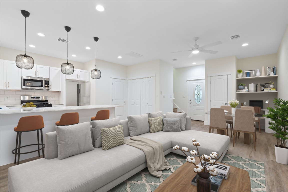 a living room with furniture kitchen view and a wooden floor